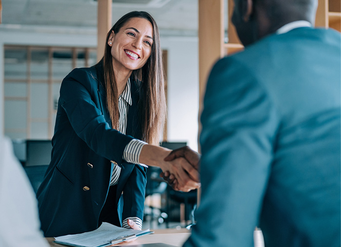 Business woman amiably shaking hands with a business man