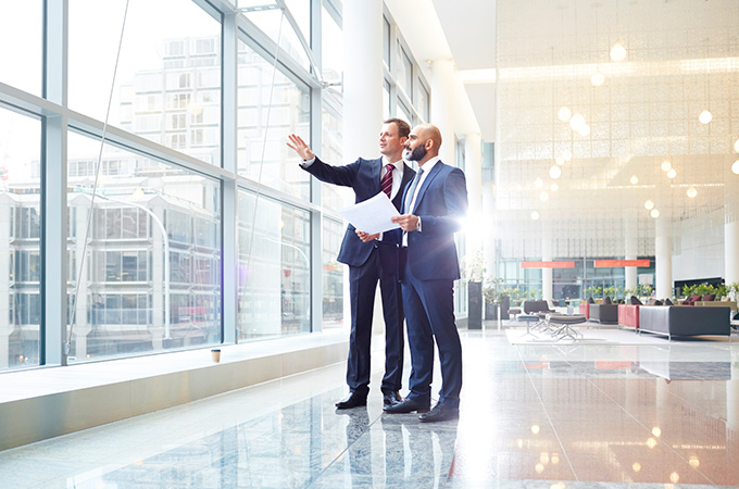 Two businessmen looking out a window and evaluating a project